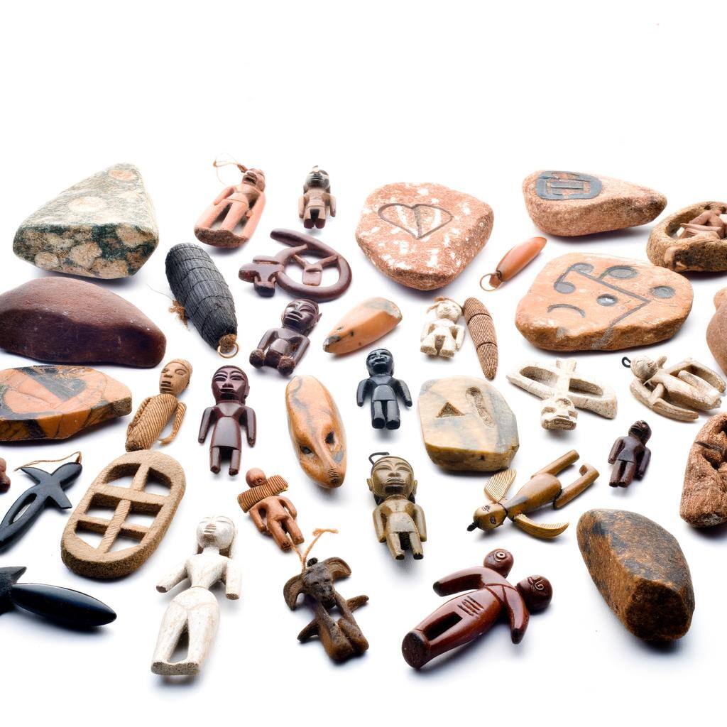 A collection of African love charms and amulets, including fetishes, stones, and symbolic carvings